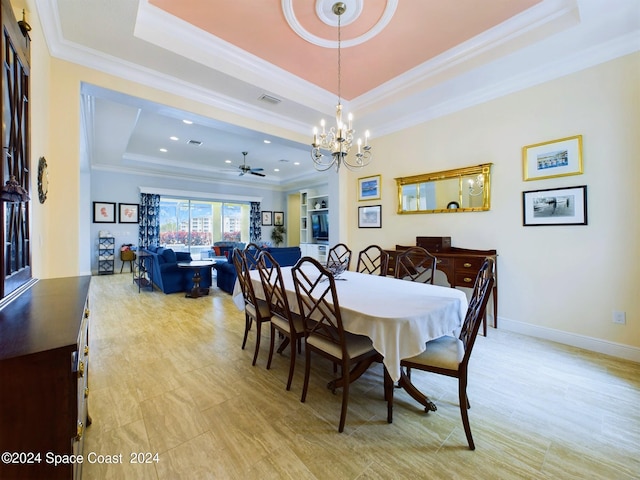 dining space with ceiling fan with notable chandelier, crown molding, and a tray ceiling