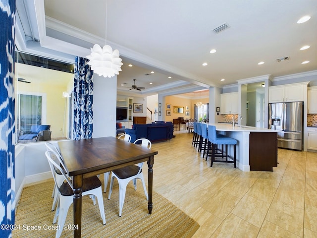 dining room featuring ceiling fan with notable chandelier, crown molding, a tray ceiling, and sink