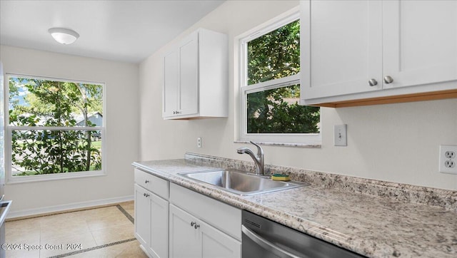 kitchen with light tile patterned flooring, white cabinetry, sink, and stainless steel dishwasher