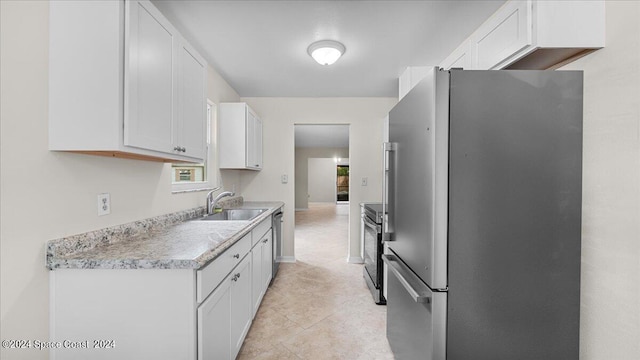 kitchen featuring appliances with stainless steel finishes, light tile patterned flooring, sink, and white cabinets