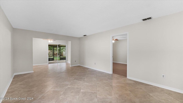 empty room with ceiling fan and a textured ceiling