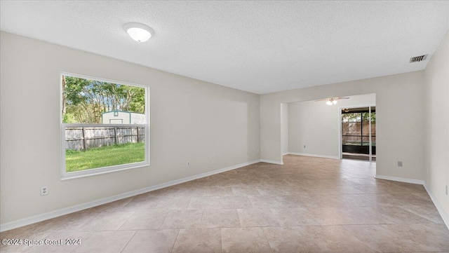 spare room with ceiling fan, a textured ceiling, and plenty of natural light