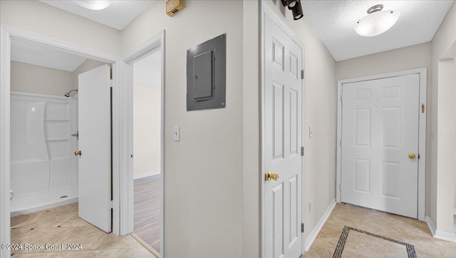 hallway featuring electric panel, light tile patterned floors, and a textured ceiling