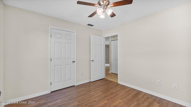 unfurnished bedroom featuring ceiling fan, hardwood / wood-style flooring, and a textured ceiling