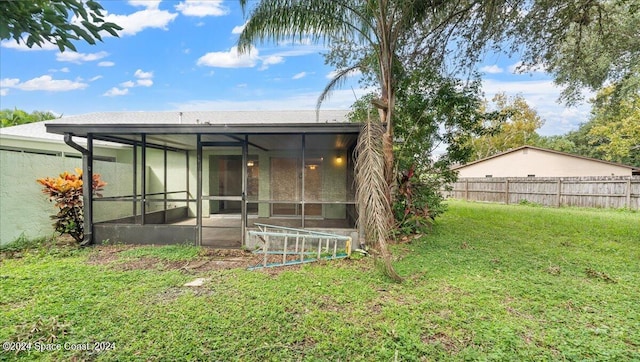 rear view of property featuring a sunroom and a lawn