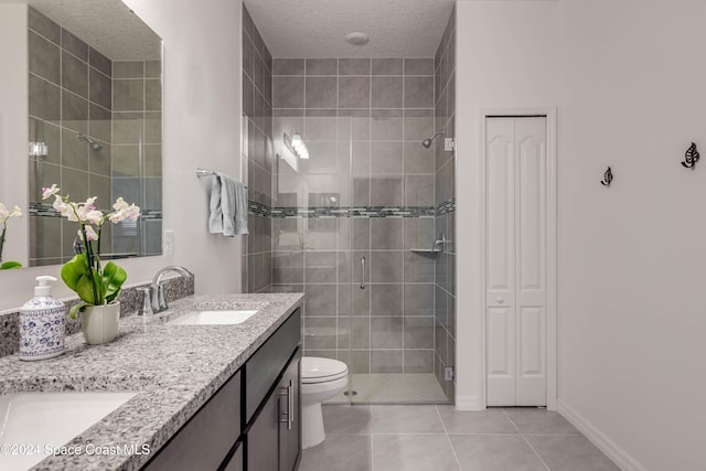 bathroom featuring tile patterned flooring, toilet, a shower with door, vanity, and a textured ceiling