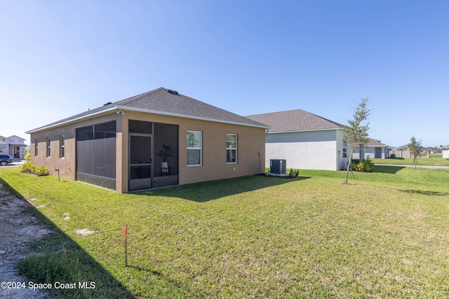 rear view of house featuring central AC unit, a sunroom, and a yard