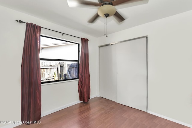 unfurnished bedroom with baseboards, a ceiling fan, a closet, and wood finished floors