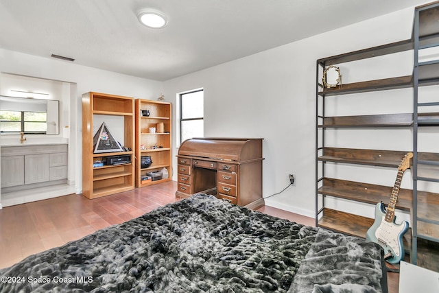 bedroom with multiple windows, connected bathroom, wood finished floors, and visible vents