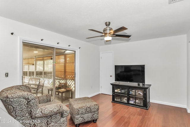 living room featuring baseboards, a ceiling fan, and wood finished floors