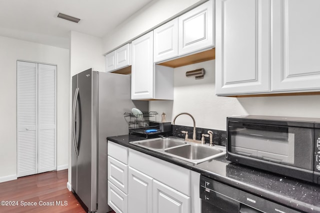 kitchen featuring dark wood-style flooring, a sink, white cabinetry, visible vents, and black appliances