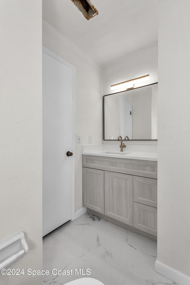 bathroom with vanity, marble finish floor, and baseboards