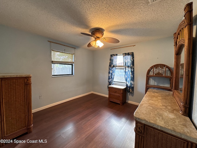 unfurnished bedroom featuring a textured ceiling, ceiling fan, dark wood-style floors, and multiple windows