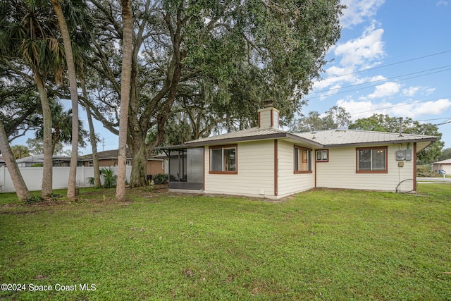 back of house featuring a lawn and a sunroom