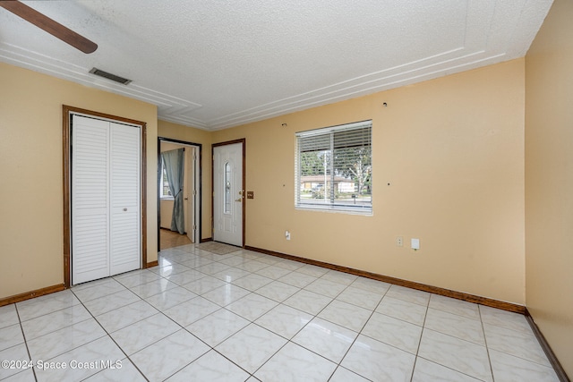 tiled spare room featuring a textured ceiling