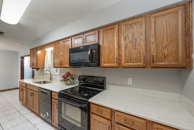 kitchen with black appliances, sink, light tile patterned flooring, and a textured ceiling