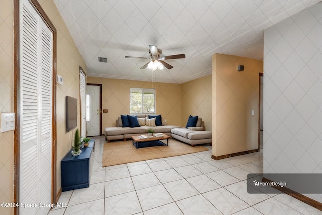 living room featuring crown molding, light tile patterned floors, and ceiling fan