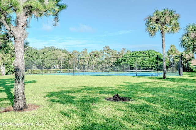 view of home's community featuring a lawn and tennis court