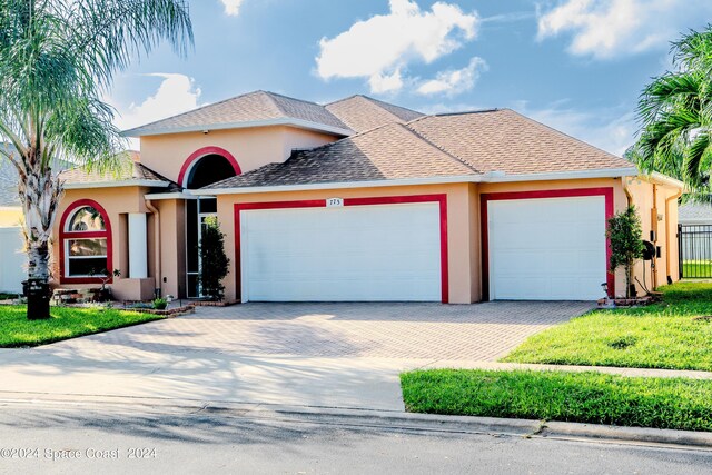 mediterranean / spanish home with an attached garage, stucco siding, driveway, and a front yard