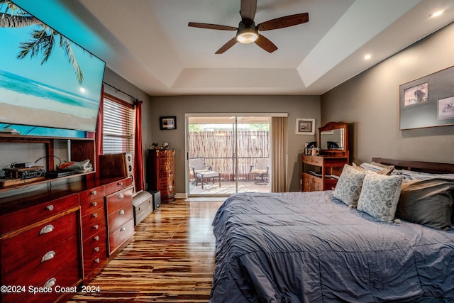 bedroom featuring access to exterior, a ceiling fan, recessed lighting, wood finished floors, and a tray ceiling
