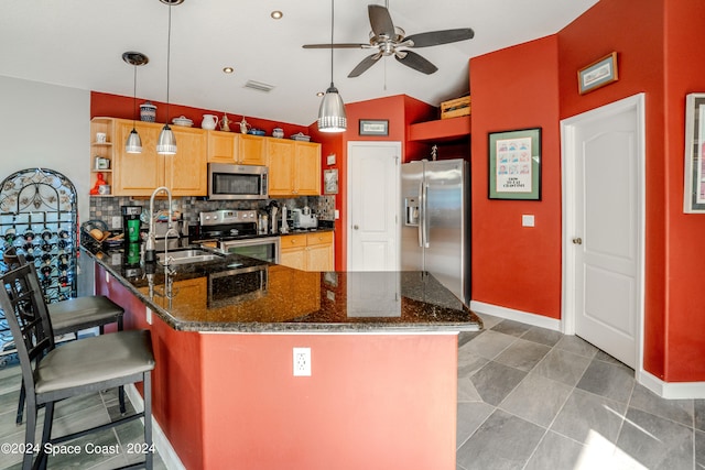 kitchen featuring tasteful backsplash, vaulted ceiling, kitchen peninsula, hanging light fixtures, and appliances with stainless steel finishes