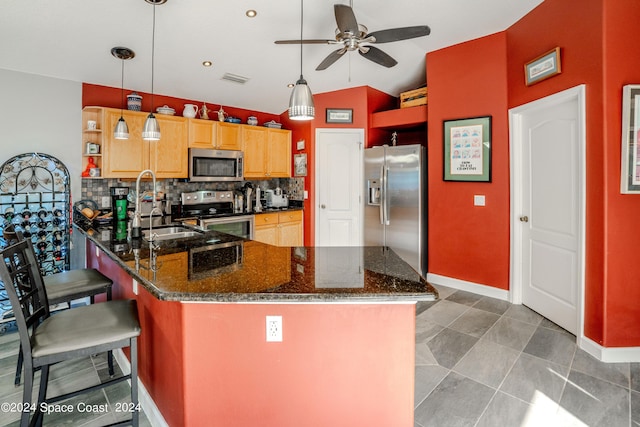 kitchen with ceiling fan, appliances with stainless steel finishes, a peninsula, tasteful backsplash, and vaulted ceiling