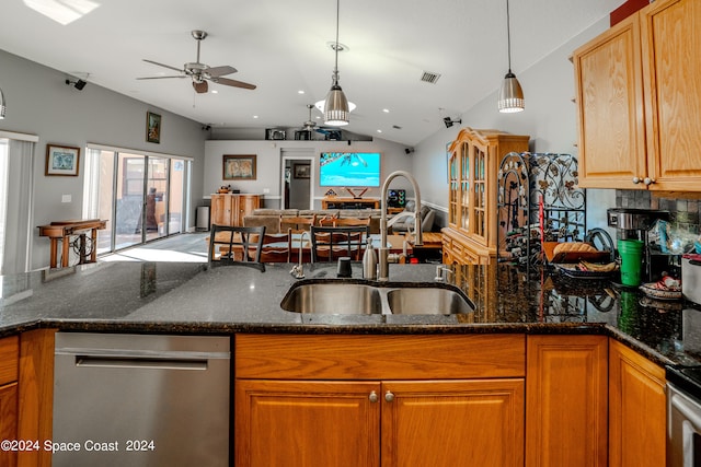 kitchen featuring dark stone countertops, lofted ceiling, sink, and stainless steel dishwasher