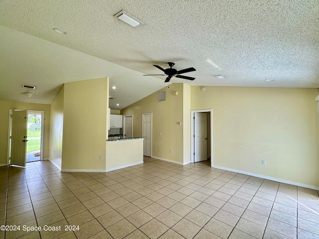 unfurnished living room with ceiling fan, light tile patterned floors, a textured ceiling, and vaulted ceiling