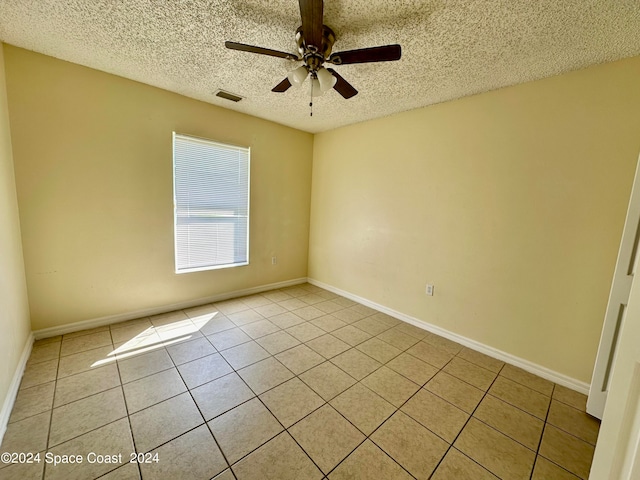 tiled empty room with ceiling fan and a textured ceiling