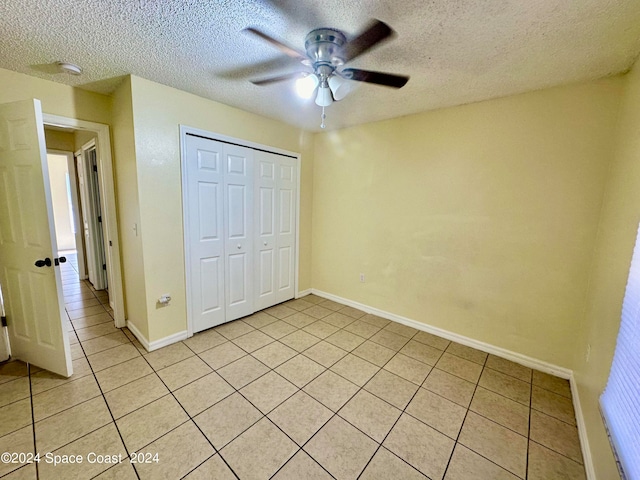 unfurnished bedroom featuring ceiling fan, a closet, light tile patterned floors, and a textured ceiling