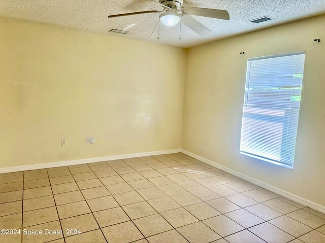 spare room with a wealth of natural light, light tile patterned floors, and a textured ceiling