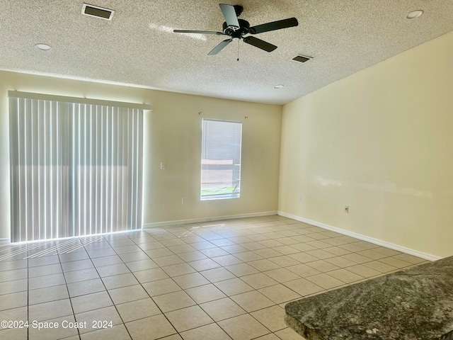 tiled empty room with ceiling fan and a textured ceiling