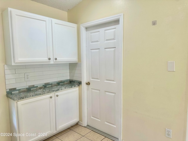 kitchen with decorative backsplash, white cabinets, and a textured ceiling