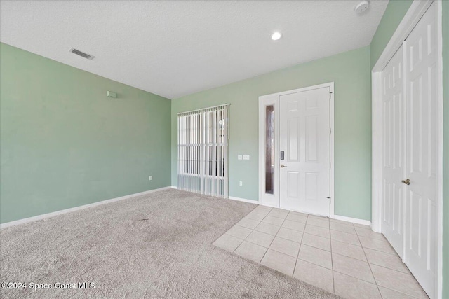 spare room with a textured ceiling and light colored carpet