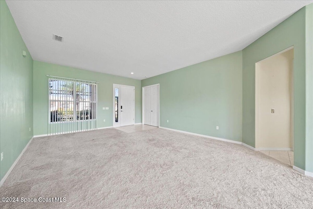 unfurnished room with light carpet and a textured ceiling