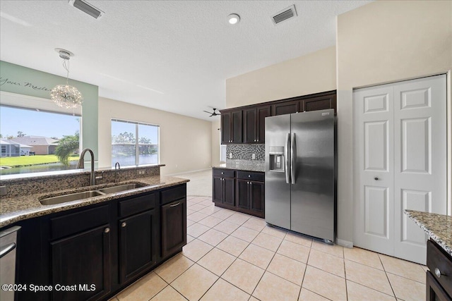 kitchen with dark brown cabinets, light tile patterned floors, appliances with stainless steel finishes, pendant lighting, and sink