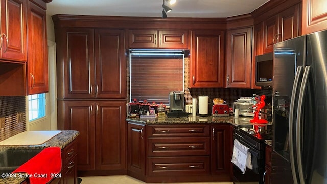 kitchen with appliances with stainless steel finishes, dark stone countertops, and tasteful backsplash