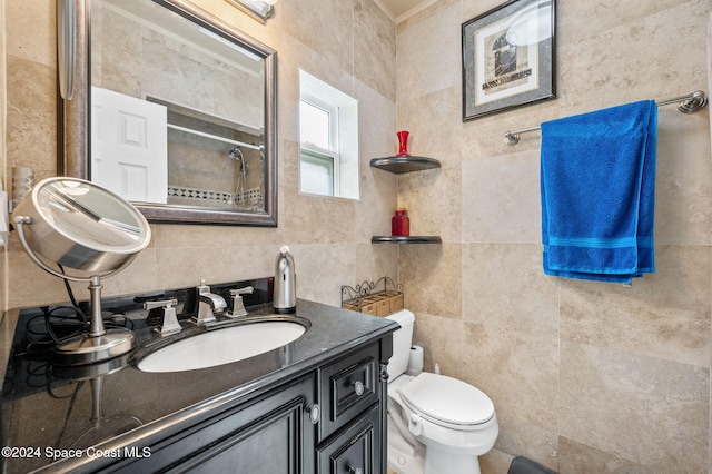 bathroom with toilet, vanity, a shower, and tile walls