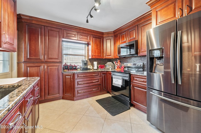 kitchen with decorative backsplash, track lighting, light tile patterned floors, appliances with stainless steel finishes, and light stone countertops