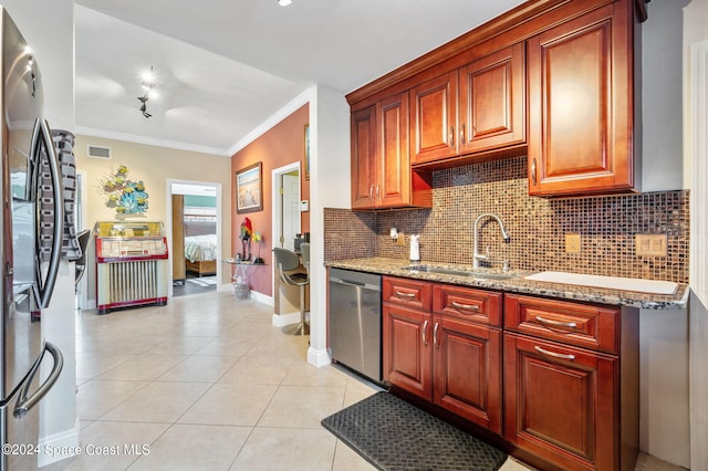 kitchen featuring light stone countertops, appliances with stainless steel finishes, sink, crown molding, and light tile patterned floors