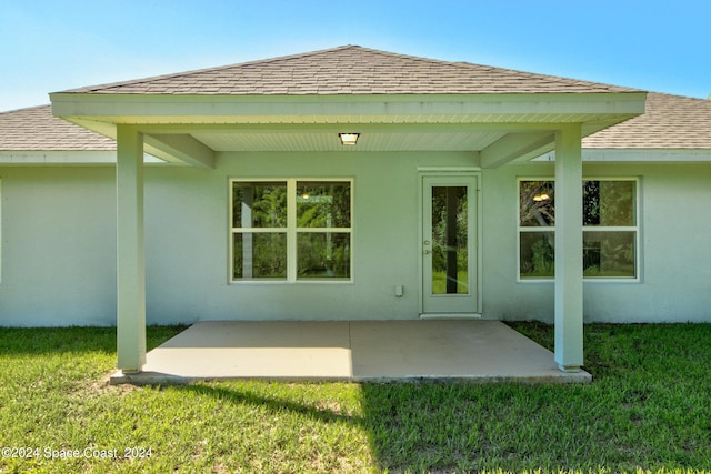 back of house with a patio and a lawn