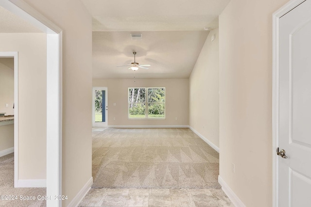 spare room featuring ceiling fan, light colored carpet, and vaulted ceiling