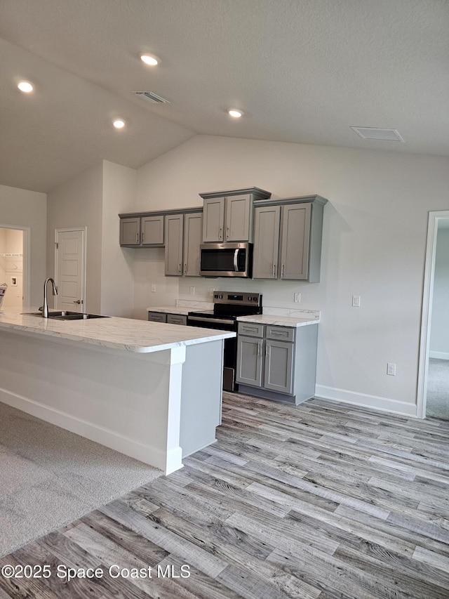 843 Geary St SW, Palm Bay, FL 32908 - kitchen with gray cabinets, appliances with stainless steel finishes, a sink, light wood-type flooring, and lofted ceiling
