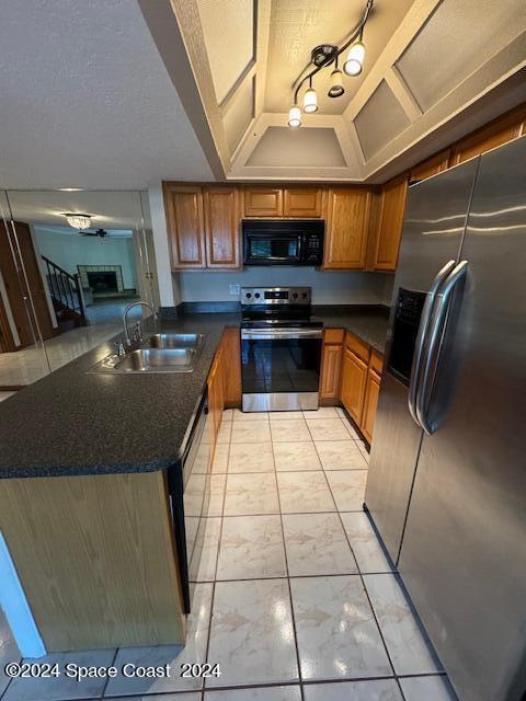 kitchen with a textured ceiling, appliances with stainless steel finishes, sink, and kitchen peninsula