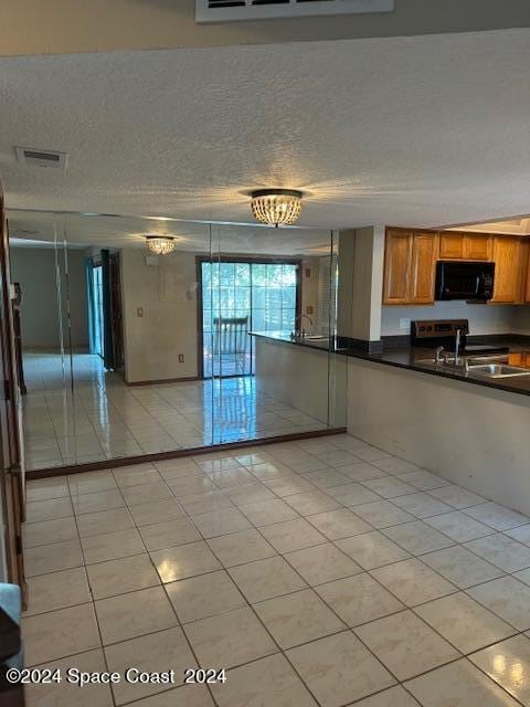 kitchen featuring light tile patterned flooring, stainless steel range with electric stovetop, and a textured ceiling