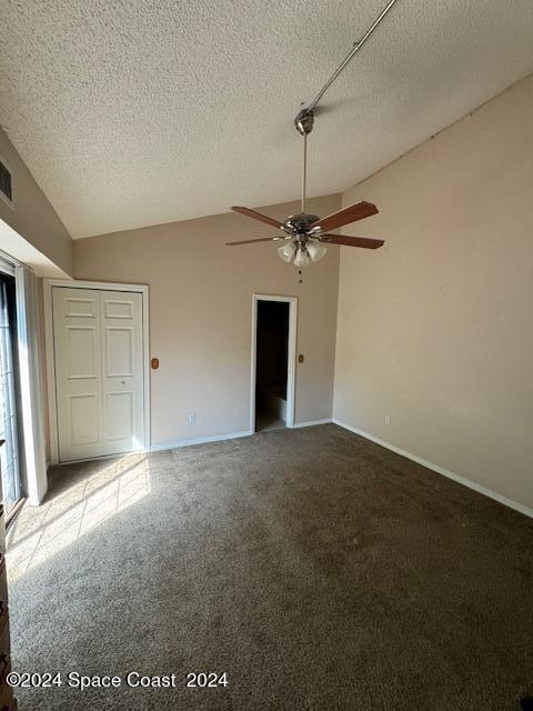 carpeted empty room featuring lofted ceiling, ceiling fan, and a textured ceiling