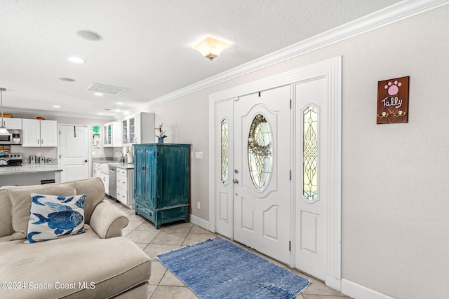 foyer entrance with ornamental molding, sink, light tile patterned floors, and a textured ceiling