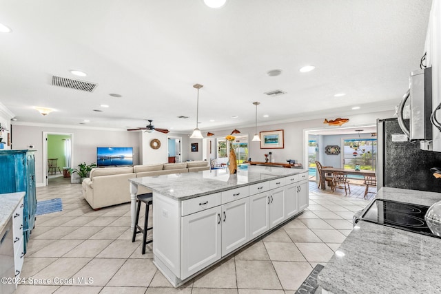 kitchen with light stone counters, pendant lighting, light tile patterned floors, and white cabinetry