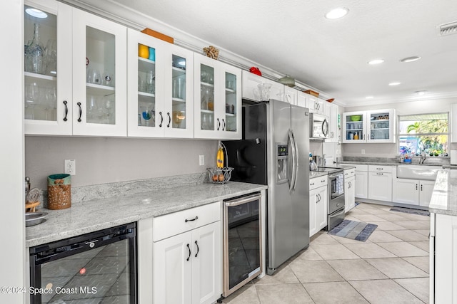 kitchen with appliances with stainless steel finishes, wine cooler, white cabinetry, and ornamental molding