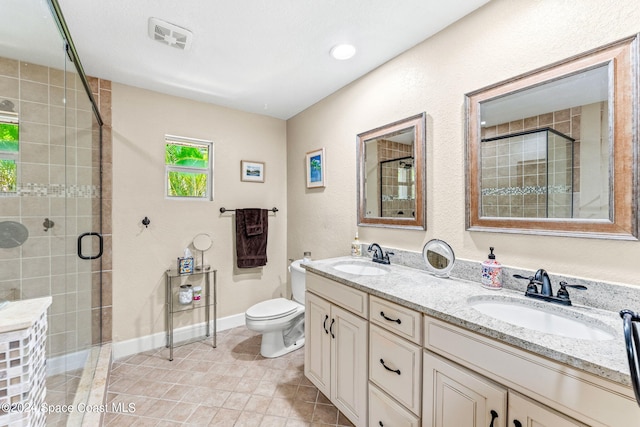 bathroom featuring tile patterned floors, vanity, toilet, and a shower with shower door